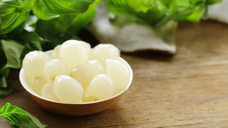 Small bowl of pickled pearl onions on wooden table