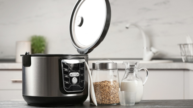 slow cooker with open lid next to jars of milk and oatmeal
