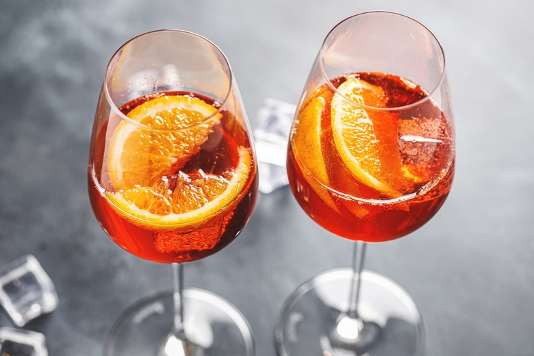 How to make aperol spritz recipe - two glasses filled halfway with red liquid, ice and orange slices