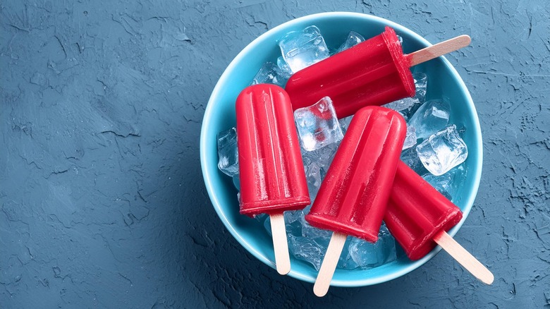 A bowl of red popsicles with ice