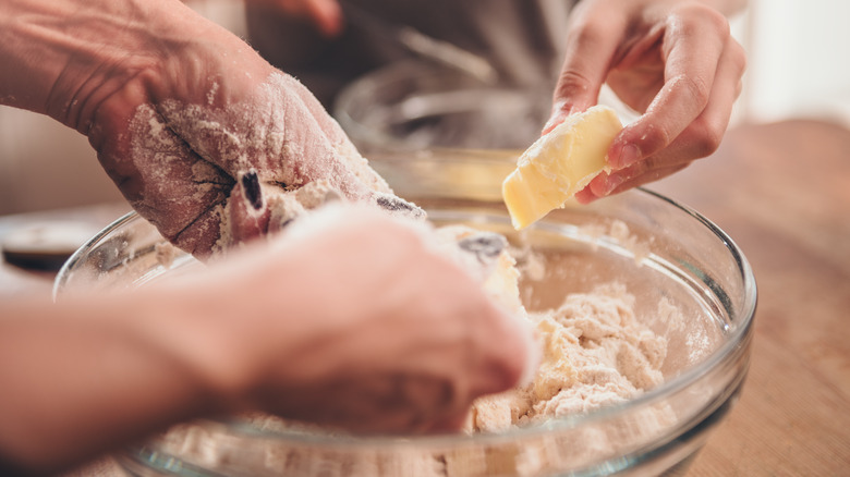 Hands mixing butter into batter