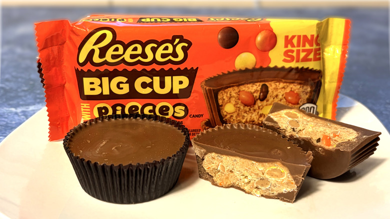 Reese's pieces cup sliced in half on a plate in front of the product package