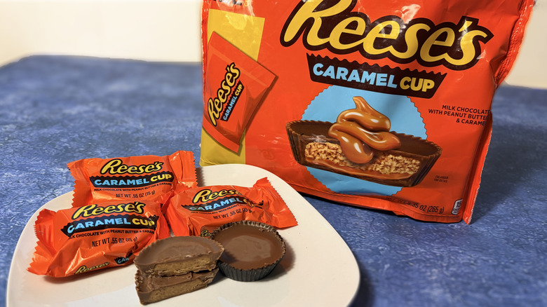 Reese's caramel cup sliced in half on a plate, in front of the product package
