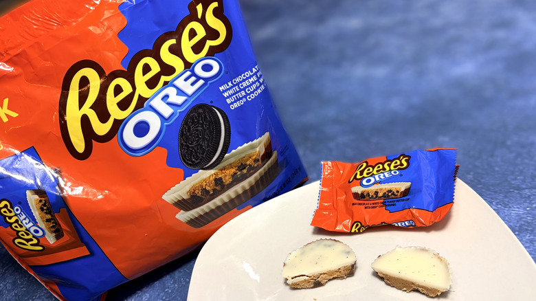 Reese's Oreo cup sliced in half on a plate, in front of the product package