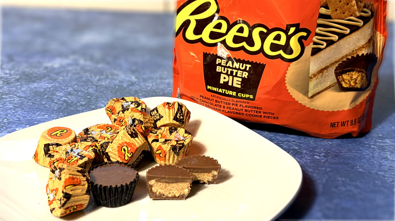 Reese's peanut butter pie cup sliced in half on a plate, in front of the product package