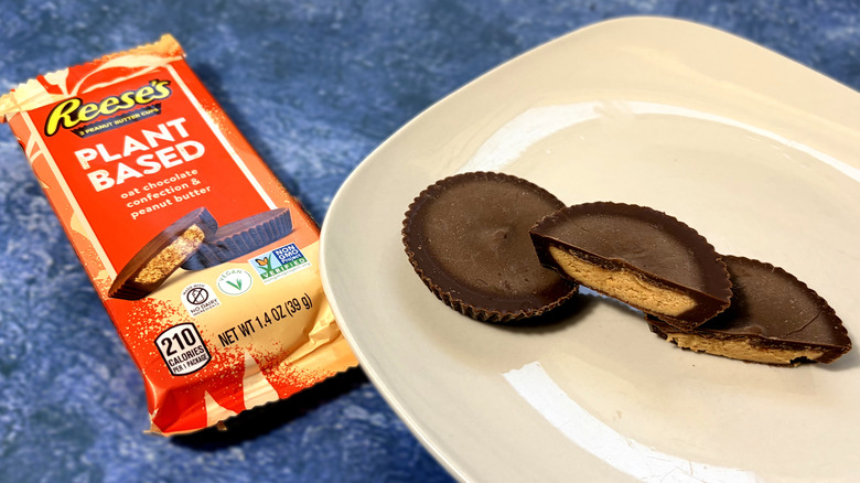 Reese's plant based cup sliced in half on a plate, next to the product package