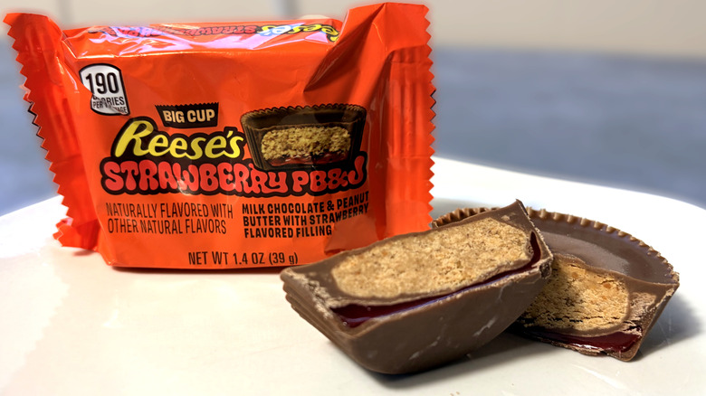 Reese's PB&J cup sliced in half on a plate, next to the product package