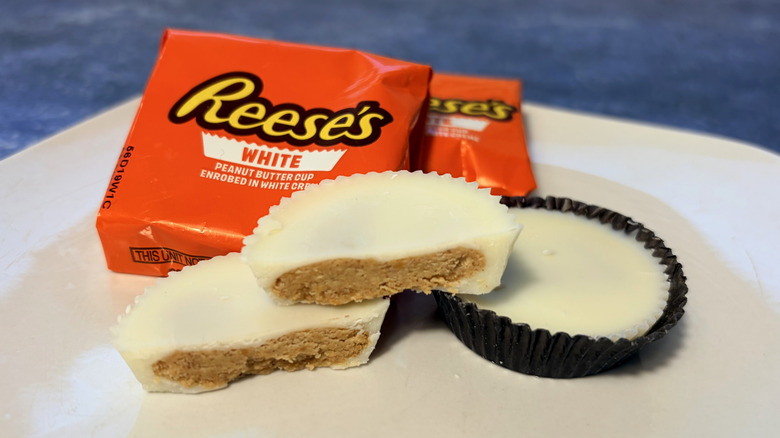 Reese's white creme cup sliced in half on a plate, in front of the product package