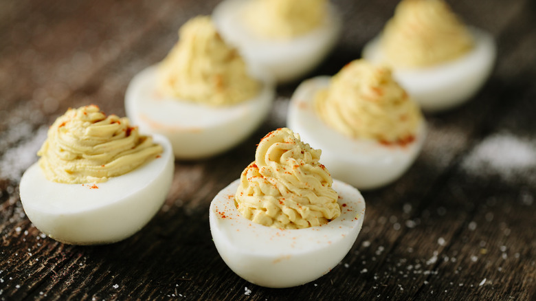 Deviled eggs with paprika as garnish on wooden board