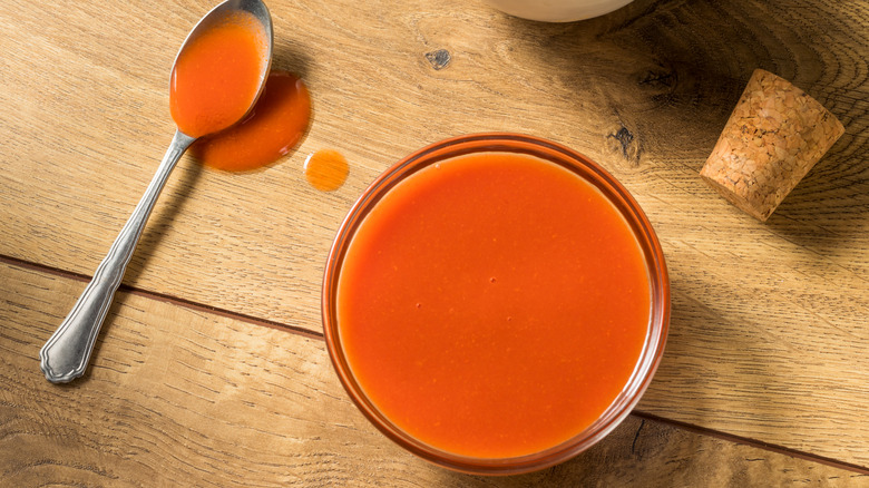 Small bowl of Buffalo sauce with metal spoon.