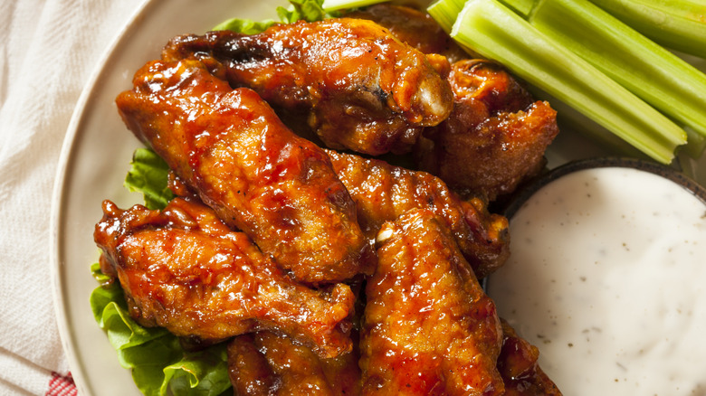 Plate of Buffalo chicken wings with celery sticks and ranch dressing.
