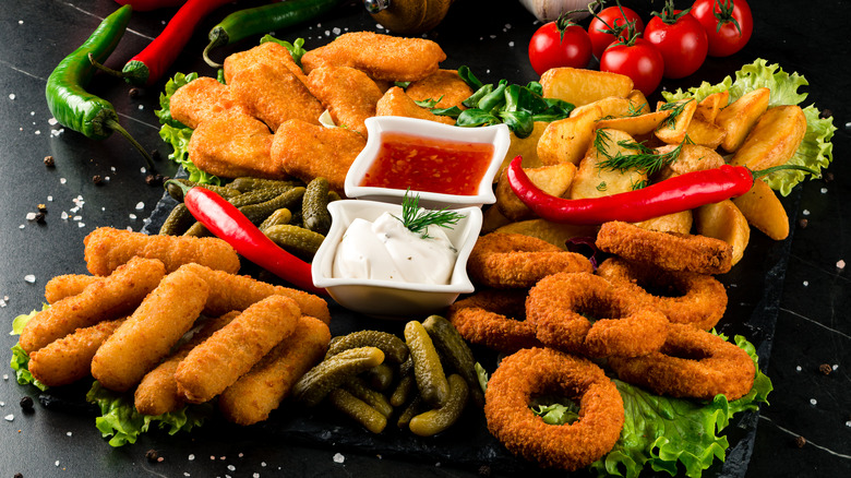 Various fried appetizers with dips on black platter.