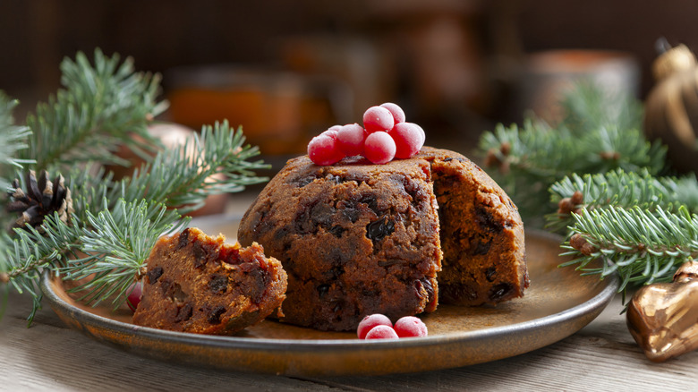Plum pudding topped with fresh fruits in a plate, placed on a table