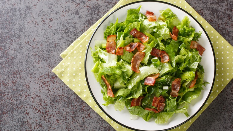 Wilted lettuce salad with bacon bits on plate