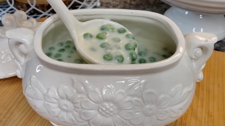 A vintage serving dish full of creamed peas