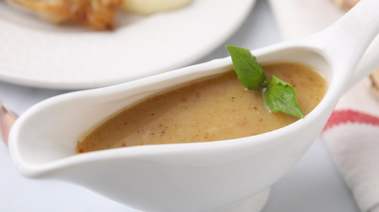 A boat of turkey gravy, garnished with a sprig of basil