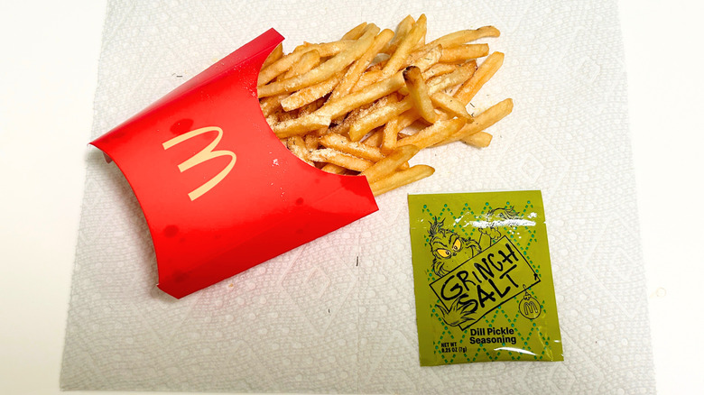A packet of Grinch Salt and seasoned fries against a textured white background
