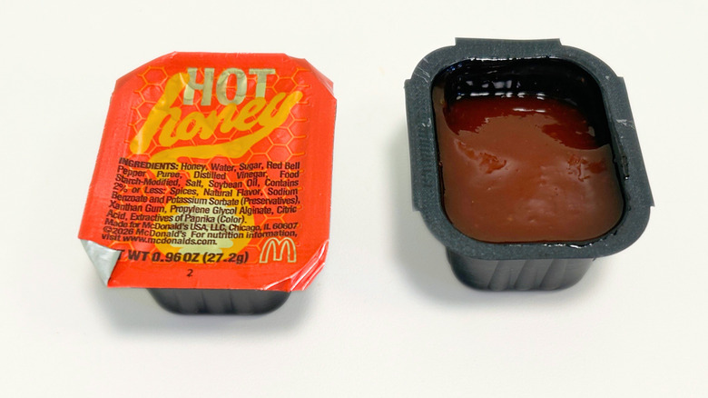 An opened and an unopened Hot Honey Sauce packet from McDonald's