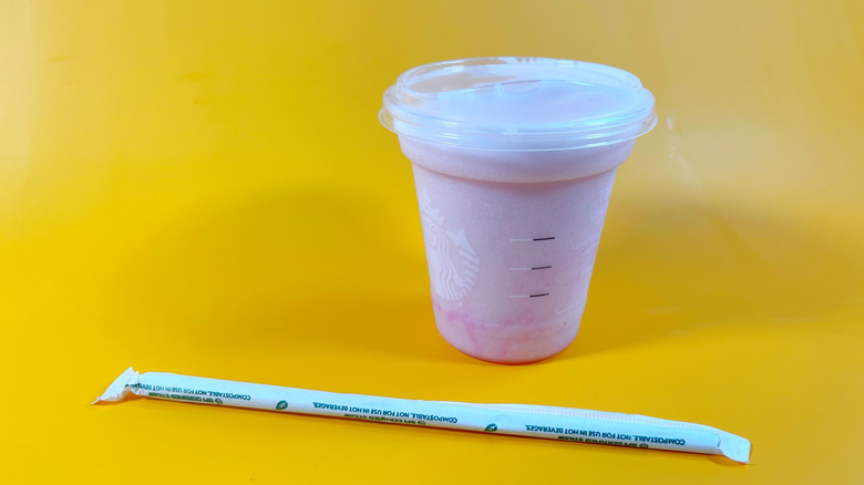The Pink Energy Blended Refresher with a straw on an orange background