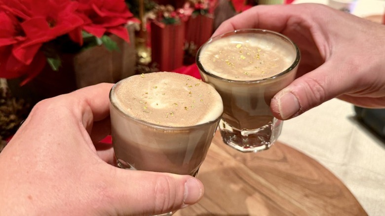 Two hands holding Caramel Miso Hot Cocoas from Starbucks and clinking the glasses