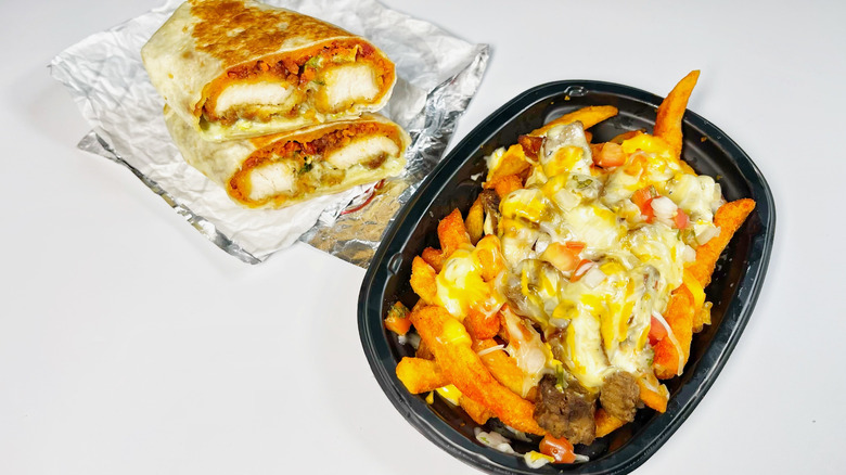 The nacho fries and chipotle burrito cut in half on a white background