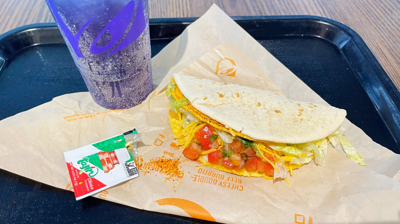 The Tajín Cheesy Gordita Crunch on a tray with a Tajín packet and Midnight Baja Blast