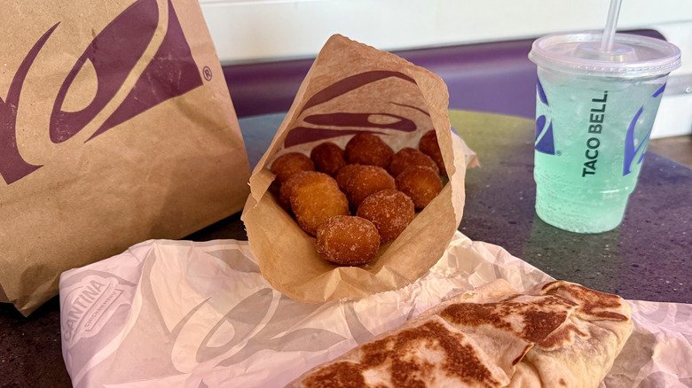 A bag of Cinnabon Delights, a burrito, and drink at Taco Bell