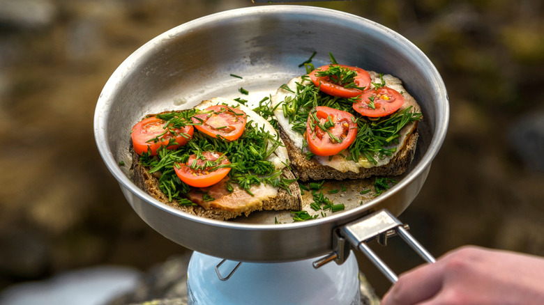Person cooking food using a camp pan and camp stove
