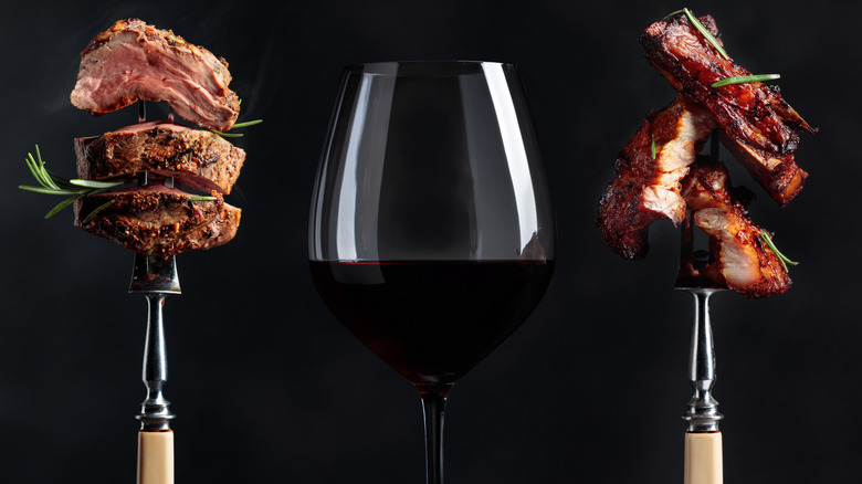Two skewers of cooked meat framing a glass of red wine