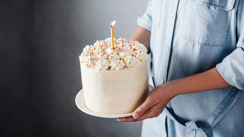 Person holding a cake with a candle on it