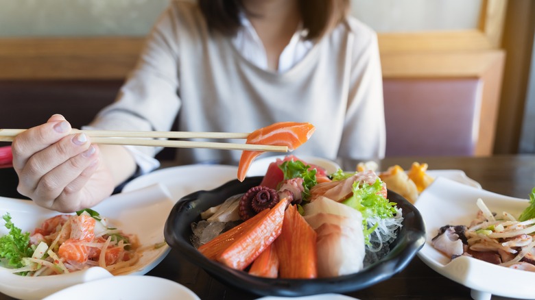 Woman eating raw salmon at restaurant 