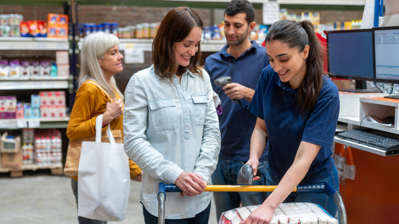 A group of people shopping together standing at a checkout station