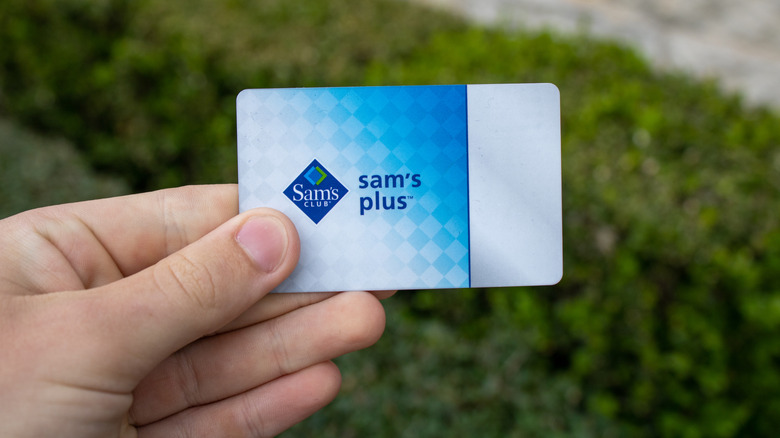 A person holds up a Sam's Club Plus Membership card