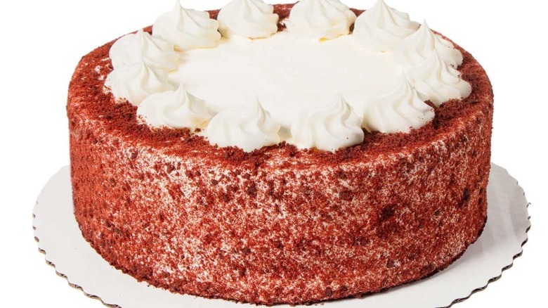 a whole red velvet cake on a tray with white frosting on top