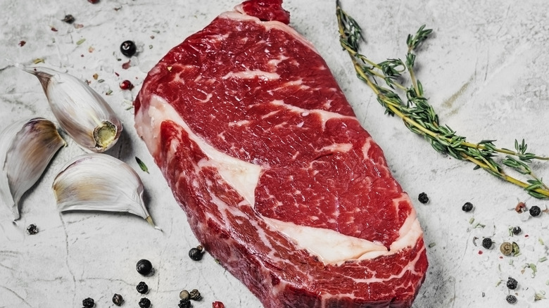 Rib eye steak with garlic and herbs on marble