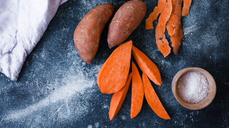 Sweet potatoes whole and sliced, plus peels on countertop