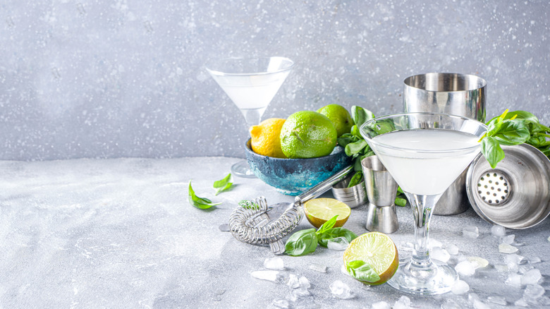 Two martinis sitting on a table surrounded by cut up lemons.