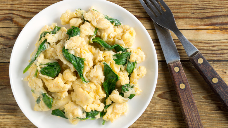 Scrambled eggs with spinach on white plate