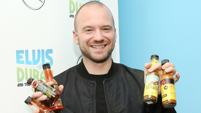 Sean Evans holding bottles of hot sauce