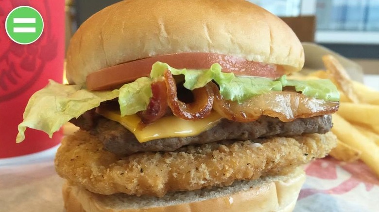 A Wendy's sandwich with a beef patty, chicken patty, bacon, lettuce, tomato, and cheese.