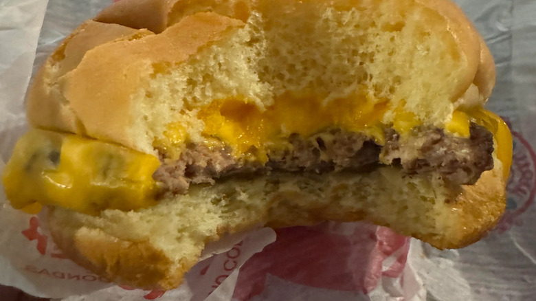 A bitten-into cross section of a Wendy's burger with cheddar sauce dripping out of the sides.