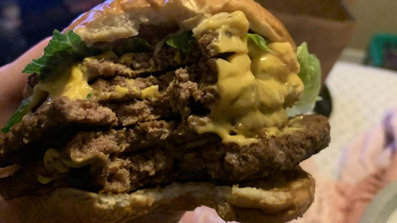 A bitten-into Wendy's burger with four beef patties.