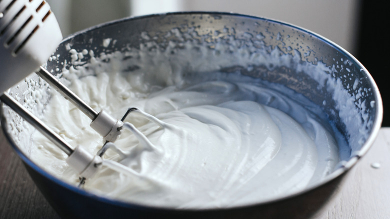 Egg whites beating in metal bowl