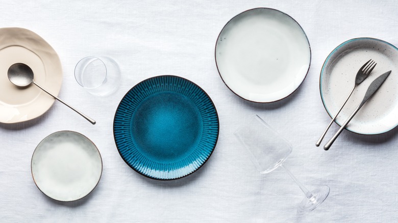 Single blue plate next to other white plates