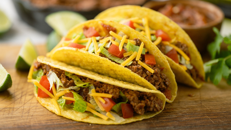 A man smiling while eating a taco in his kitchen.