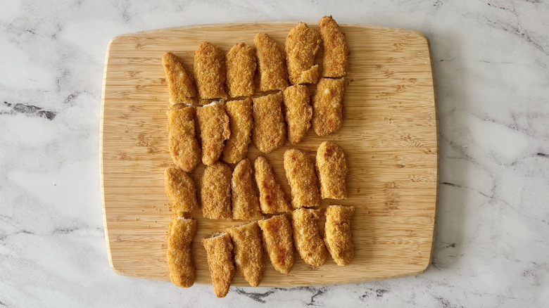 Halved chicken strips on cutting board