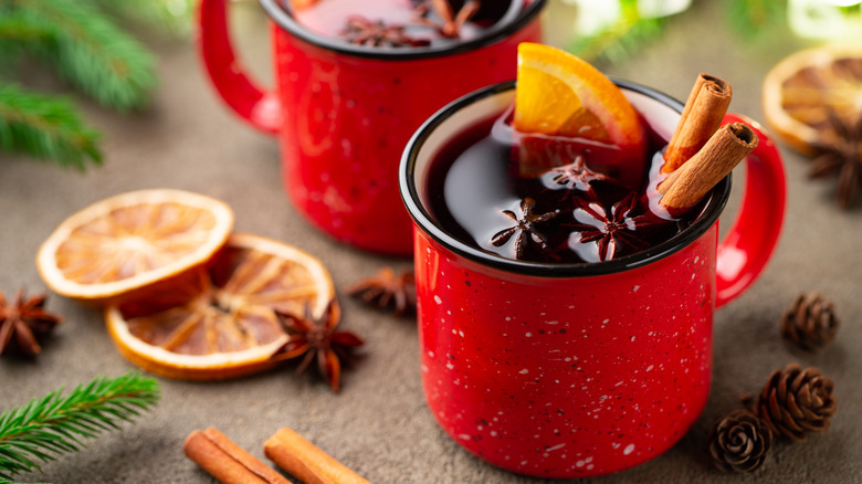 Red tin mugs filled with mulled wine and spices