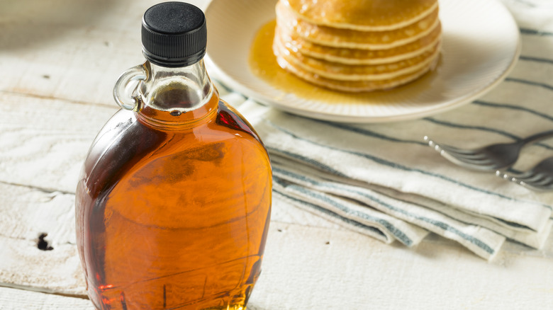 Maple syrup in glass bottle on wooden table 