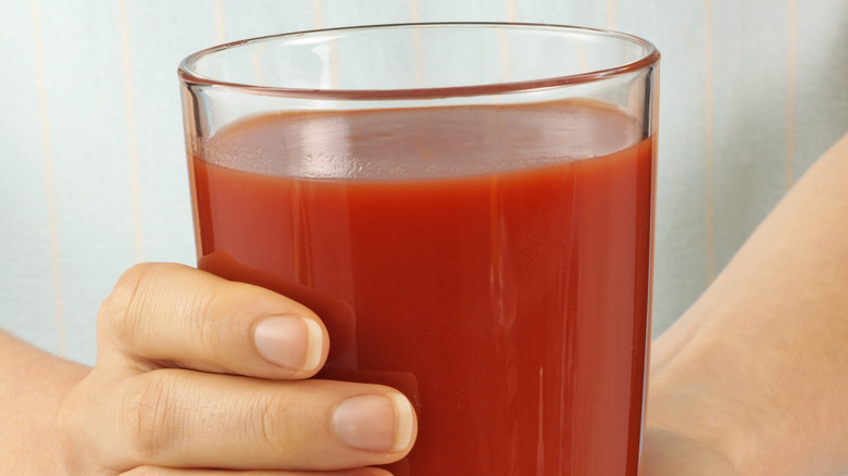 person holding glass of red juice