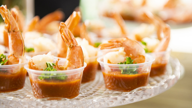 Shrimp cocktail on a crystal plate in miniature cups of cocktail sauce